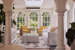 A sunlit room with a high ceiling, large windows, and a geometric patterned floor. - Raes on Wategos (Byron Bay)