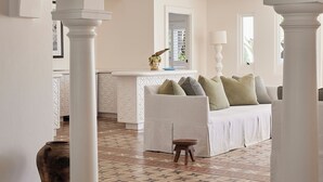 A spacious living area with a white sofa, a coffee table, and a decorative vase. There are white columns and a patterned floor. - Raes on Wategos  (Byron Bay)