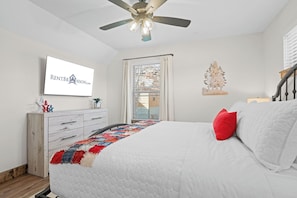 A bedroom with a bed, a ceiling fan, a TV on the wall, a window with curtains, and a decorative tree. - Tall Timbers Cabin, Private Hot Tub, Outdoor Pool, Free Daily Tickets & Near Thunder Ridge (Hollister)