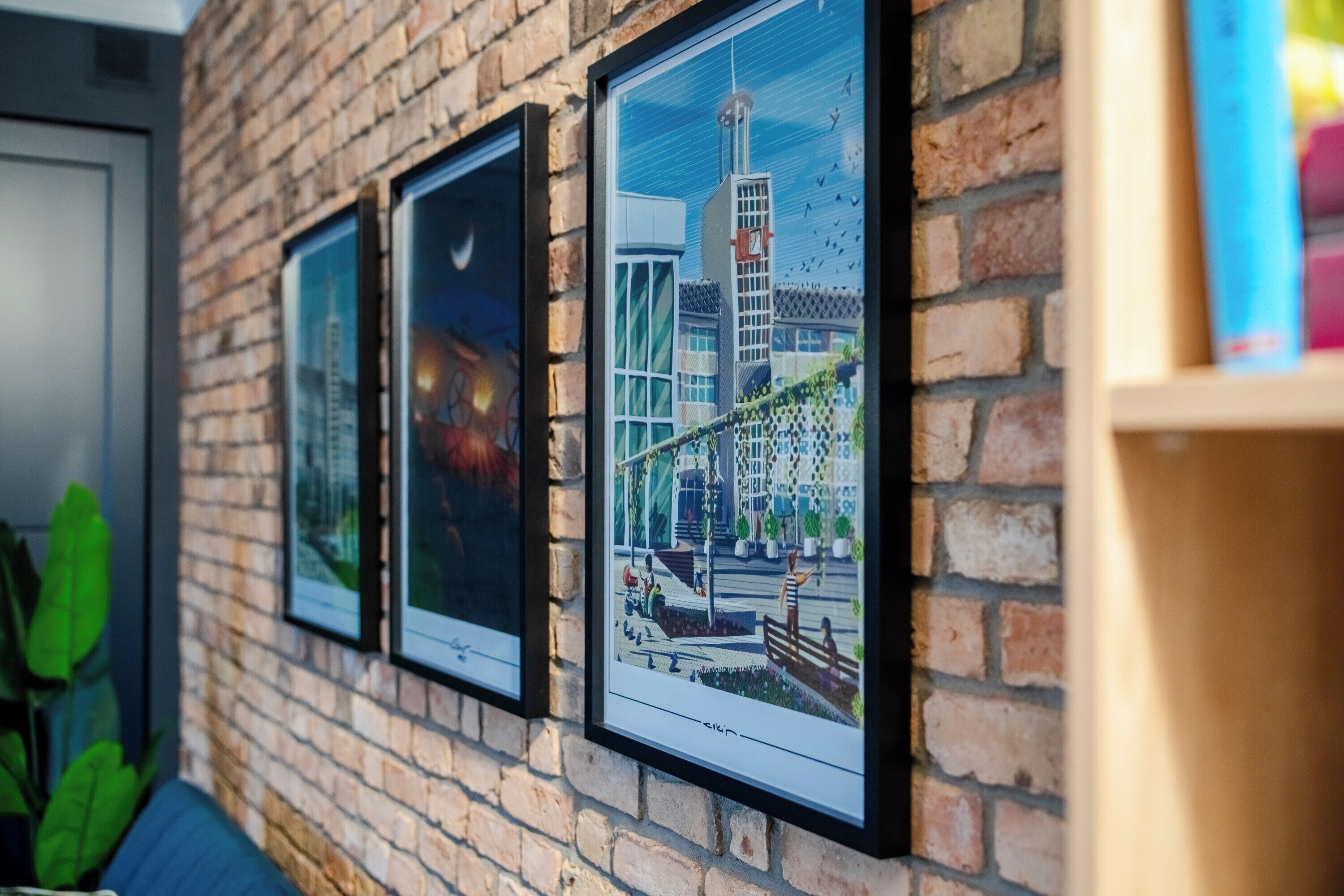 Framed cityscape photographs on a brick wall.