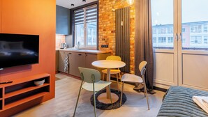 A modern living room with a TV, seating area, and a view of the city through large windows. - Koszalin Młyńska Deluxe Apartment (Koszalin)