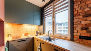A modern kitchen with a large window, a sink, and a countertop with various items. - Koszalin Młyńska Deluxe Apartment (Koszalin)