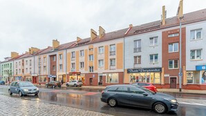 A row of multi-story buildings with a cobblestone street in front. - Koszalin Młyńska Deluxe Apartment (Koszalin)
