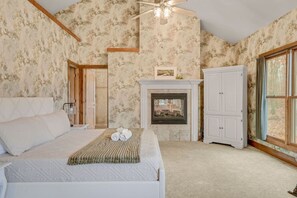 A bedroom with a bed, a fireplace, a wardrobe, and a large window. - Wine Country Waterfront • 100 Acres • Sleeps 16 (Jefferson)
