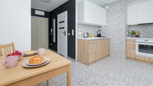 Una cocina moderna con armarios blancos, salpicadero moteado y una mesa de madera con alimentos para el desayuno.