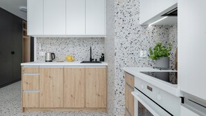 Una cocina moderna con armarios blancos, salpicadero moteado y horno integrado.