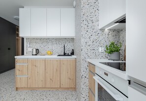 A modern kitchen with white cabinetry, a speckled backsplash, and a built-in oven. - Szczecin Bronowicka Comfort Studio 530 (Szczecin)