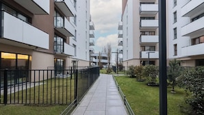 A pathway leading to a modern apartment building with balconies, a well-maintained lawn, and a clear sky. - Szczecin Bronowicka Cosy Studio 532 (Szczecin)