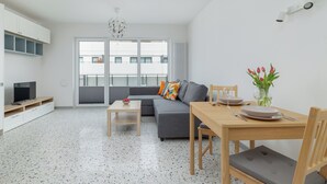 A modern living room with a grey sofa, a wooden dining table, and a TV on a white cabinet. - Szczecin Bronowicka Cosy Studio 532 (Szczecin)