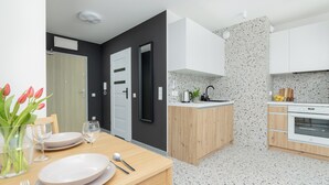 A modern kitchen with white cabinets, a granite countertop, and a built-in oven. - Szczecin Bronowicka Cosy Studio 532 (Szczecin)