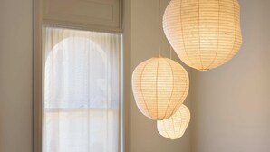 Une pièce avec une fenêtre, un berceau et des lanternes en papier suspendues.