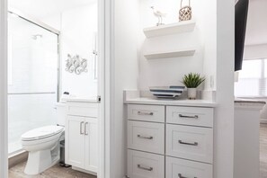 Ein modernes Badezimmer mit Toilette, einer Duschkabine aus Glas und einem Waschtisch mit Schubladen und Ablage.