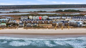 Eine Küstenwohngegend mit Immobilien direkt am Strand, darunter mehrstöckige Gebäude mit Balkonen und ein Strand im Vordergrund.