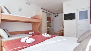 Ein Hotelzimmer mit Etagenbett, Schreibtisch, Stuhl, Fernseher und einer Tür.
