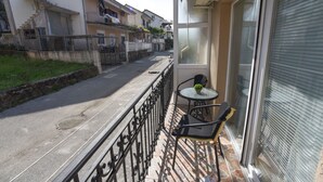 Ein Balkon mit einem kleinen Tisch und zwei Stühlen, mit Blick auf eine Wohnstraße.