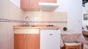 Eine kompakte Küche mit Holzausstattung, eingebautem Spülbecken, kleinem Kühlschrank und einem Essbereich mit Tisch und Stuhl.