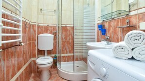 A bathroom with a glass shower enclosure, a toilet, a sink, and a washing machine. - Studio für 3 Personen by Interhome (Tivat)