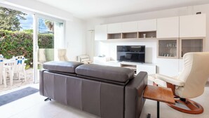 Ein modernes Wohnzimmer mit grauem Sofa, einem Holztisch, einem Fernseher und einem weißen Schrank.