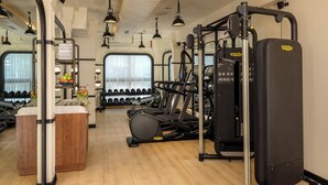 Un gimnasio con equipo de ejercicio, un espejo y una ventana con persianas.