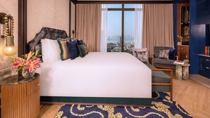 Habitación de hotel con una cama grande, vista a la ciudad, una mesita auxiliar pequeña y una pared de acento azul.