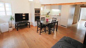 Un espacio habitable compacto con comedor, kitchenette y televisor.
