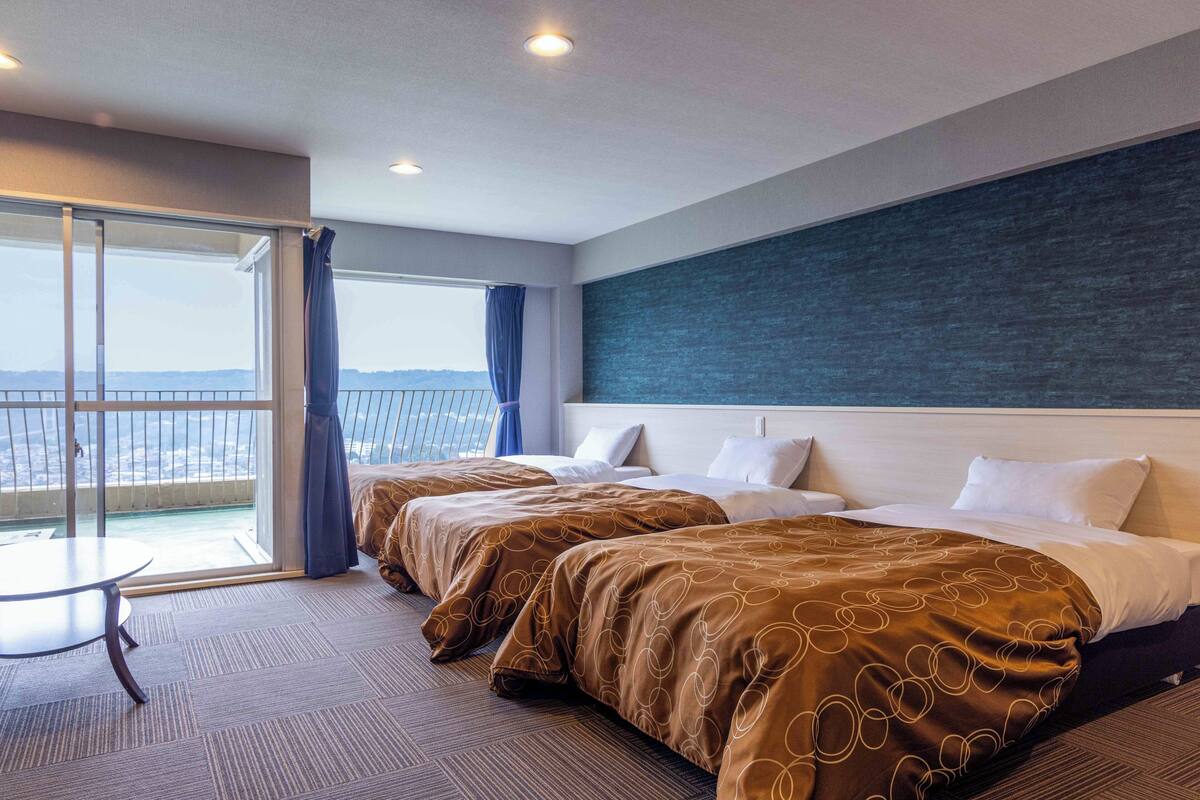 Ein Hotelzimmer mit zwei Betten, einem Balkon und einem Ausblick sowie einem Tisch.