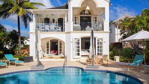 Uma casa de dois andares com piscina, área de estar externa e varanda.