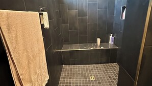 Un baño con paredes de azulejos oscuros, una bañera y piso de azulejos.