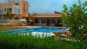Un edificio moderno con piscina, zona de estar al aire libre y un espacio cubierto.