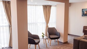Ein Hotelzimmer mit einem Bett, zwei Sesseln, einem kleinen Tisch mit einer Pflanze und einem Gemälde an der Wand.