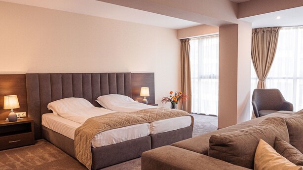 Ein Hotelzimmer mit einem großen Bett, einer Couch, einem Sessel und einem Nachttisch mit Lampe.