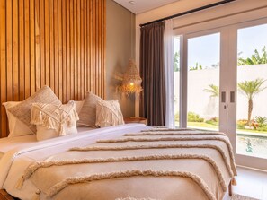 A bedroom with a bed, pillows, a hanging light fixture, and a view of the outdoors. - Haus Moana by Interhome (Seminyak)