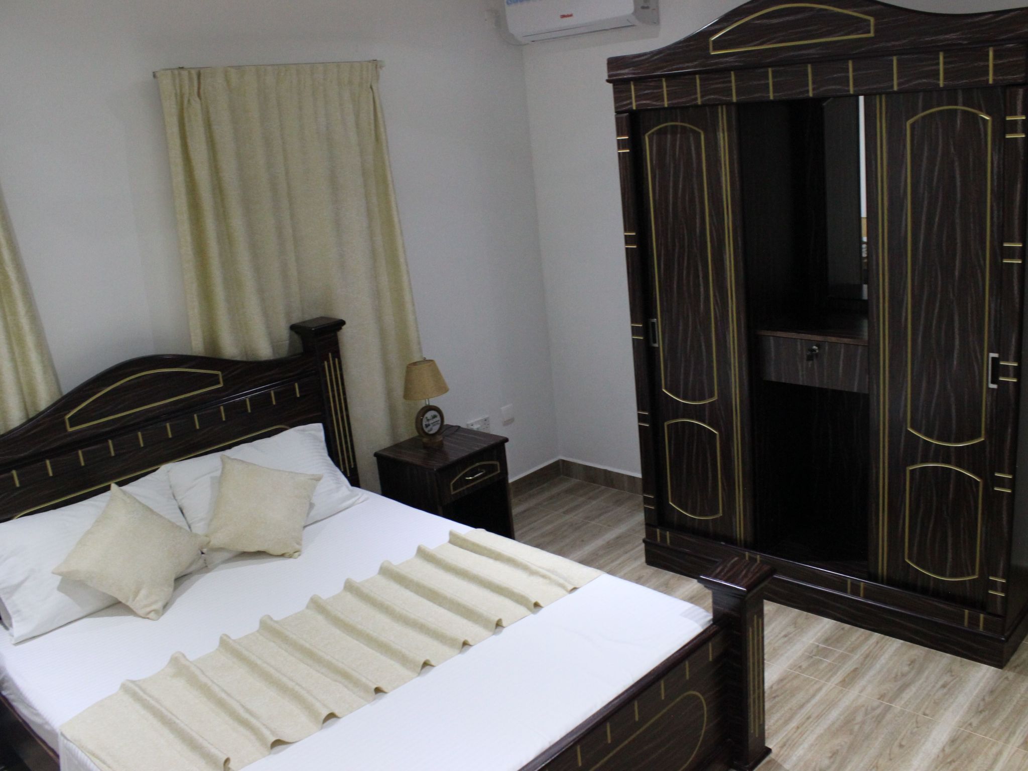 A hotel room with a bed, a nightstand, a lamp, and a wardrobe.