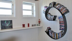 Une pièce dotée d’une bibliothèque circulaire, d’un téléviseur à écran plat, de fenêtres et d’une petite collection de figurines.