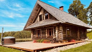A rustic log cabin with a wooden deck and a hot tub.