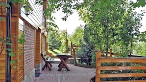 Een terras buiten met een tegelvloer, houten banken en een tafel.