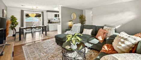 A modern living room with a dining area, kitchen, and a balcony with a view.