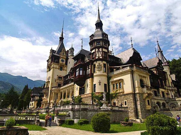 A historic castle with multiple towers, a central courtyard, and a well-maintained garden.