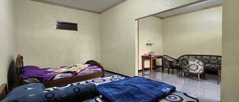A bedroom with two beds, a small table, and a sofa.