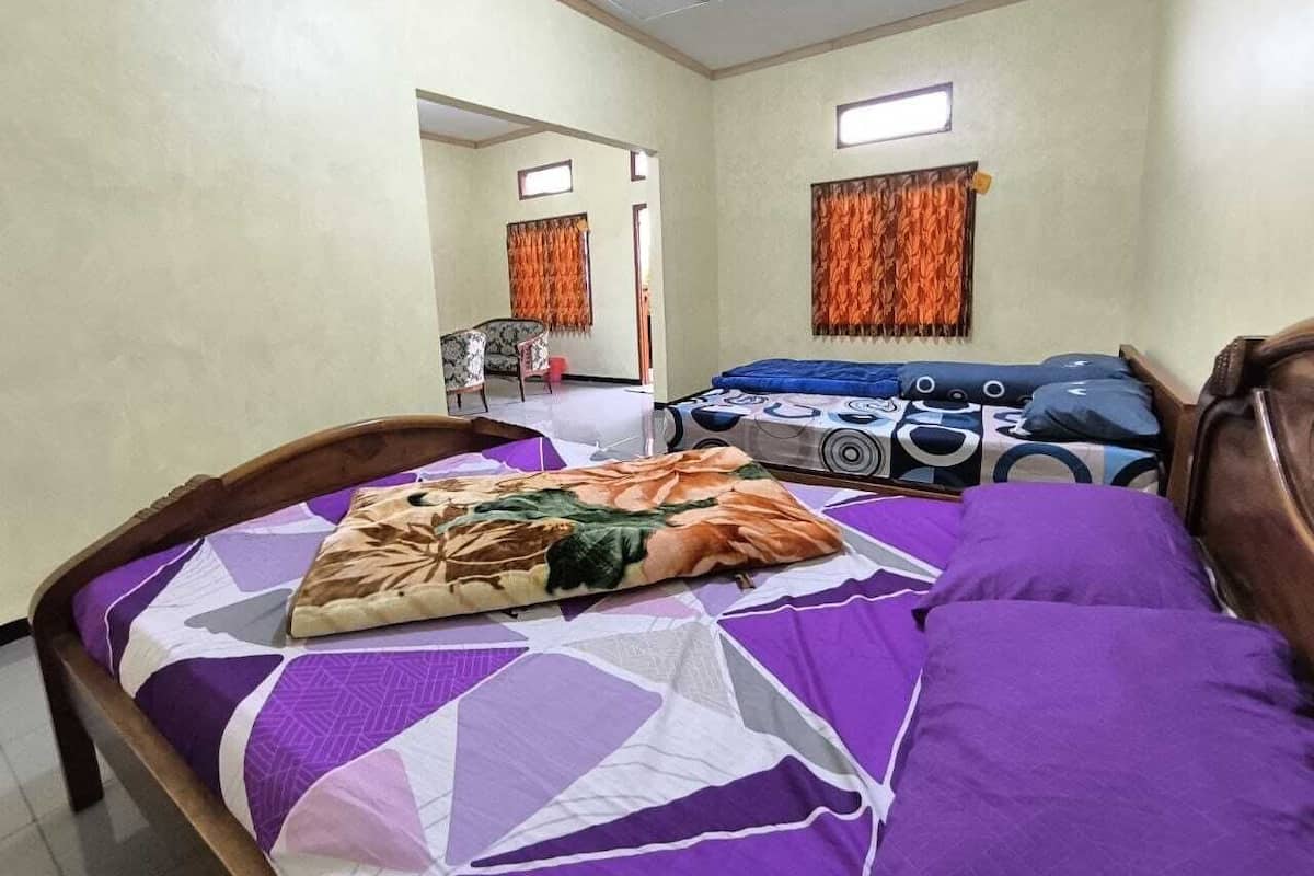 A room with a bed, a desk, and a chair. There is a window with curtains.