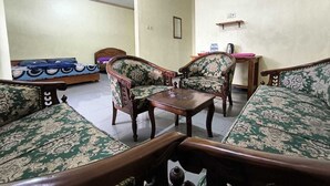 A living room with patterned sofas, a coffee table, and a bed with blue bedding. - Tengger Bromo Villa (Ngadisari)