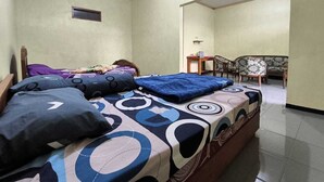 A bedroom with a bed, a nightstand, a chair, and a small table. - Tengger Bromo Villa (Ngadisari)
