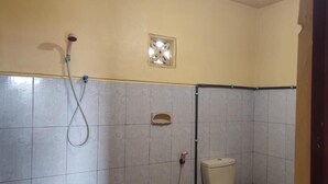 A bathroom with tiled walls, a shower with a handheld hose, and a toilet. - Tengger Bromo Villa (Ngadisari)