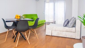 A modern living room with a dining table, a green sofa, a white sofa, and a small table with a plant. - Wohnung "Stefea Center Apart" by Interhome (Ohrid)
