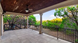 A covered patio with a ceiling fan, a tiled floor, and a view of trees and hills. - Casita W Stunning Views (Austin)