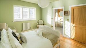 Ein Schlafzimmer mit einem großen Bett, einem Sessel, einer Heizung und einer Holztür.