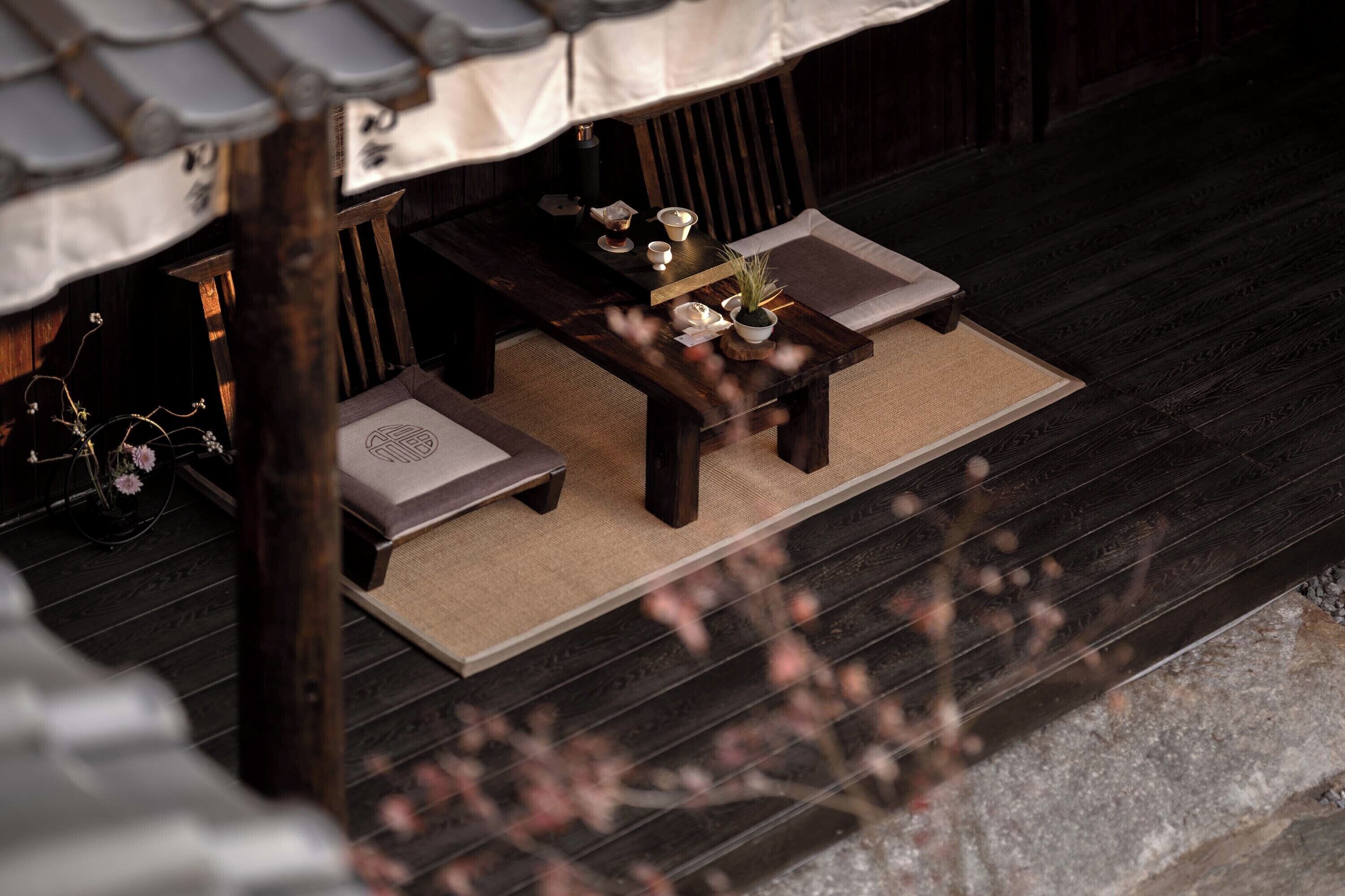 A traditional Japanese-style room with tatami flooring, a low table with a tea set, and a bicycle in the background.