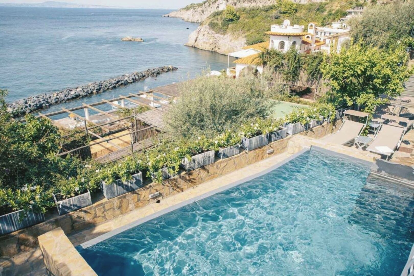 A swimming pool with a view of the sea and a rocky coastline.