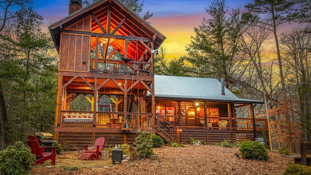 A rustic cabin with a two-story structure, a covered porch, and a deck. - Three Loves Cabin - Mountain View | Hot Tub | Pet Friendly | Firepit (Cherry Log)