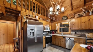 A wooden cabin kitchen with a stainless steel refrigerator, oven, microwave, and dishwasher. - Three Loves Cabin - Mountain View | Hot Tub | Pet Friendly | Firepit (Cherry Log)